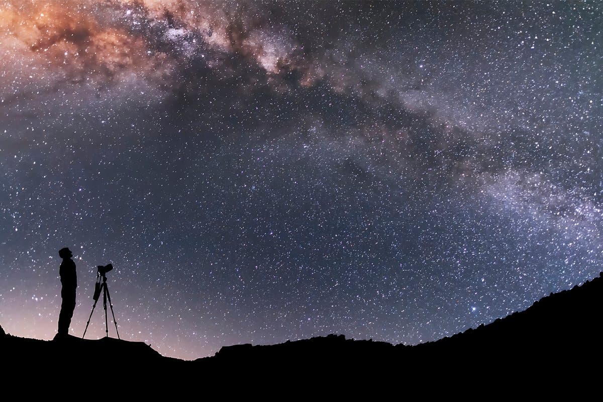 Céu estrelado da Chapada dos Veadeiros: a faixa da Via Láctea atravessa a noite com o núcleo incandescente sobre a crista escura dos morros